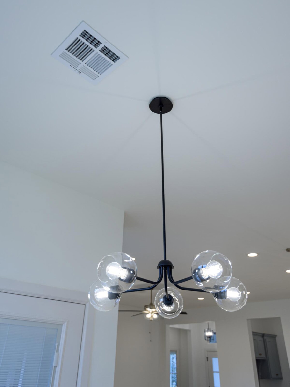A chandelier hanging in a room with a ceiling fan