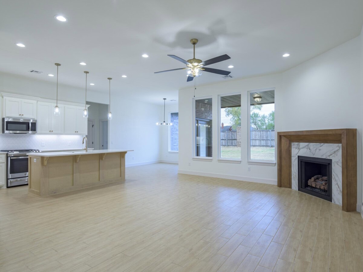A large empty kitchen with a ceiling fan and fireplace
