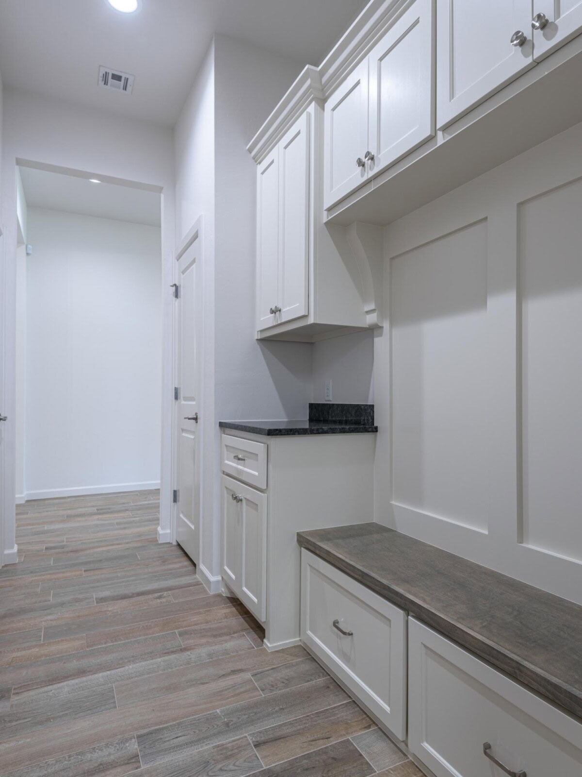 A white kitchen with cabinets and a bench