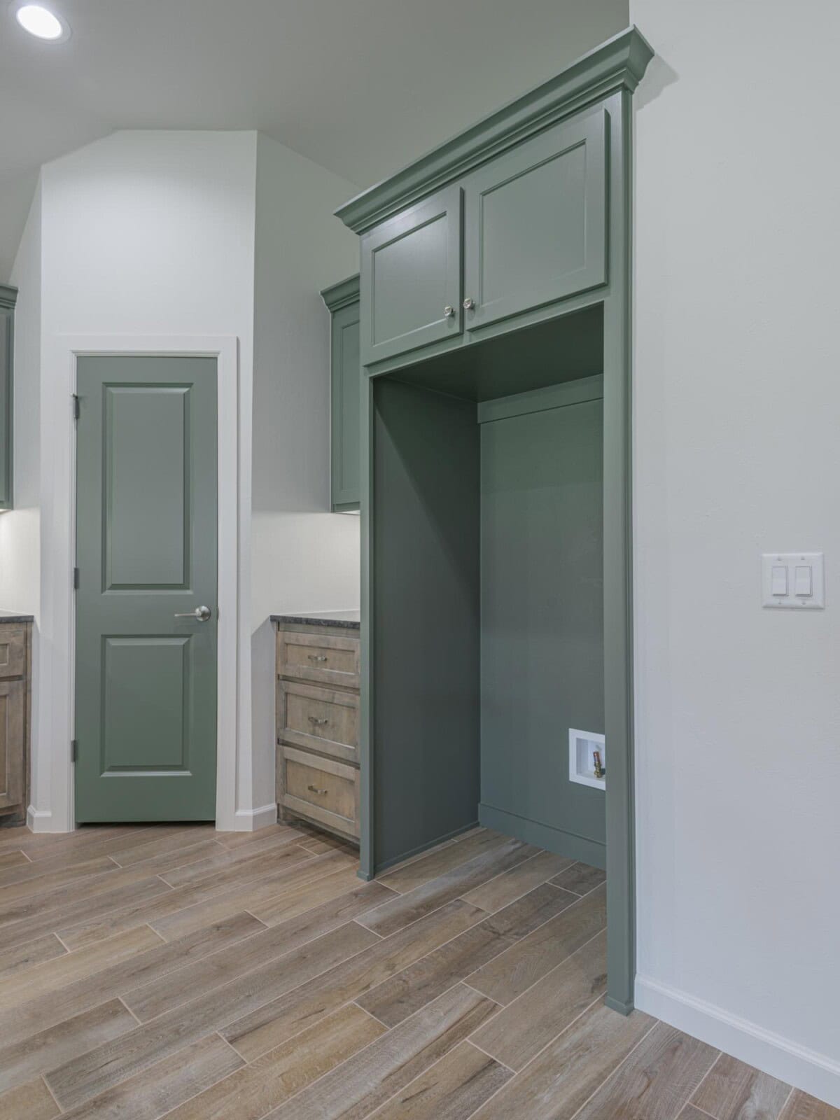 A kitchen with green cabinets and wood floors