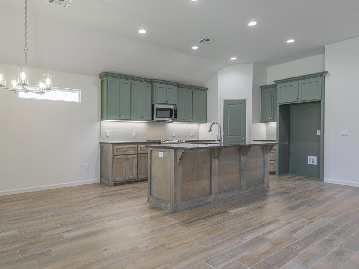 A kitchen with hardwood floors and green cabinets