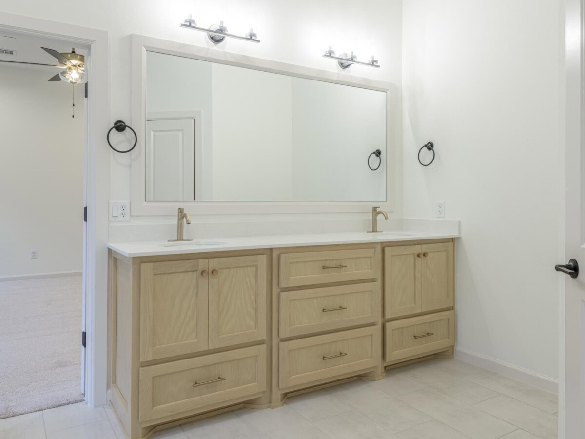 A bathroom with a large mirror and white cabinets