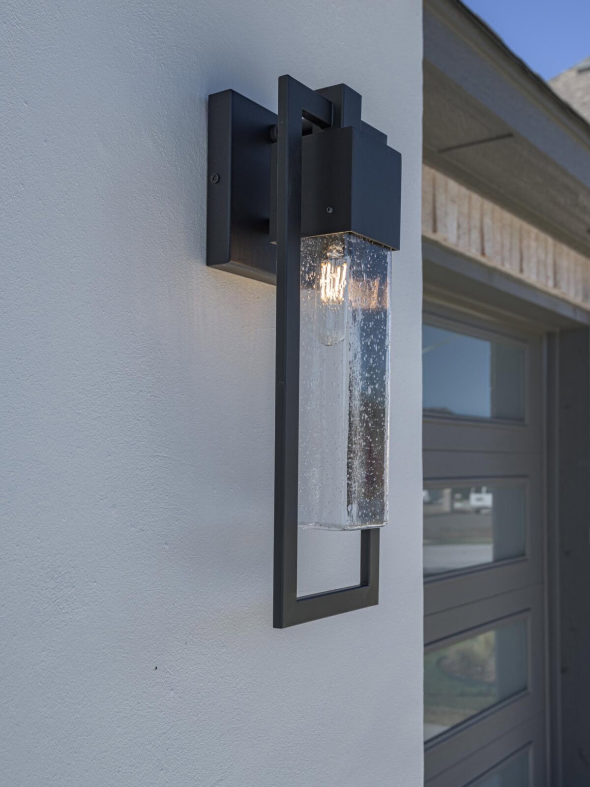 A modern outdoor wall light with a glass holder