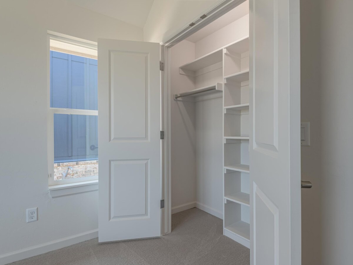 A closet with open shelves and a window