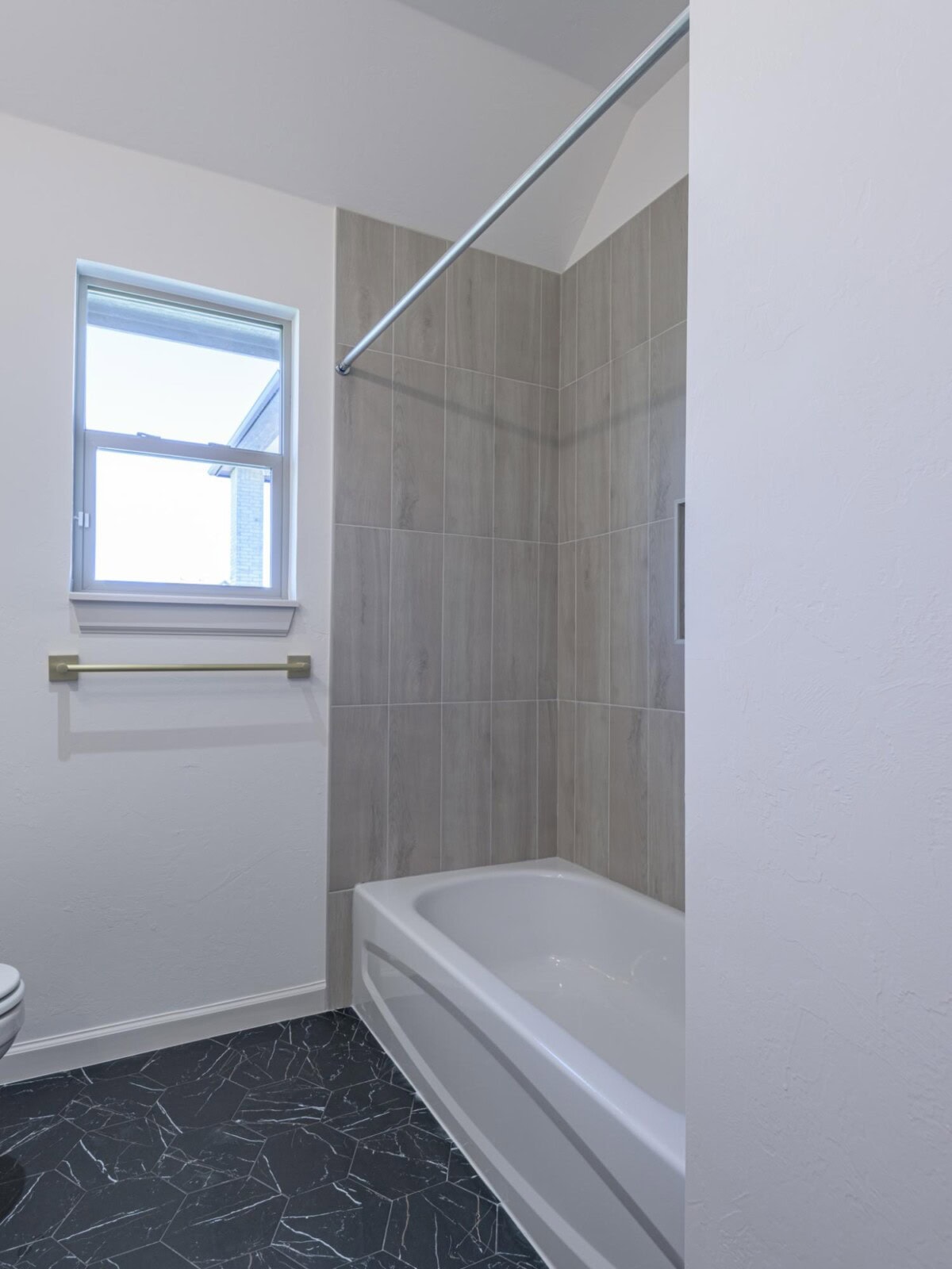 A bathroom with a toilet, bathtub, and window
