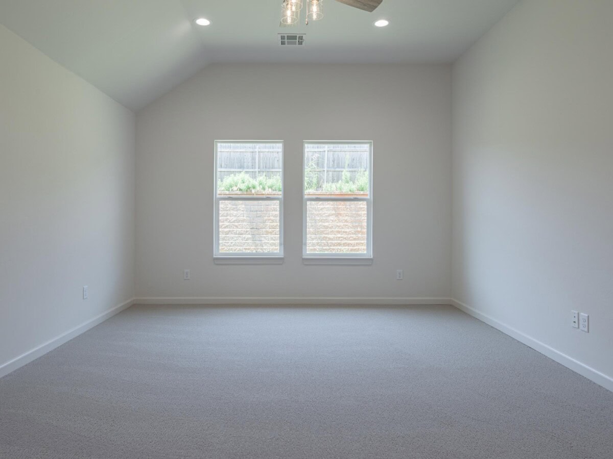 A empty room with a ceiling fan and two windows