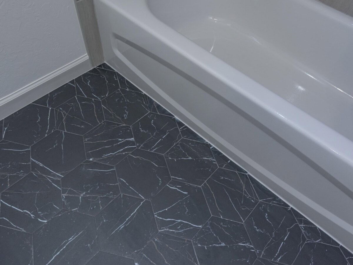 A bathroom with a white tub and black floor