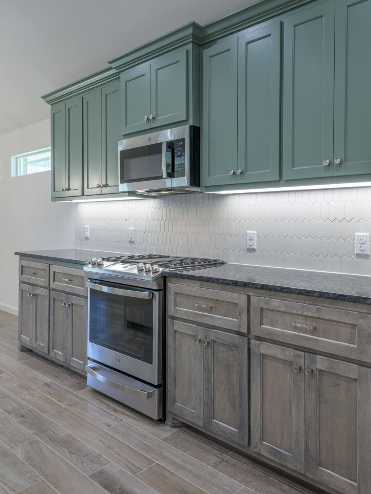 A kitchen with green cabinets and stainless steel appliances