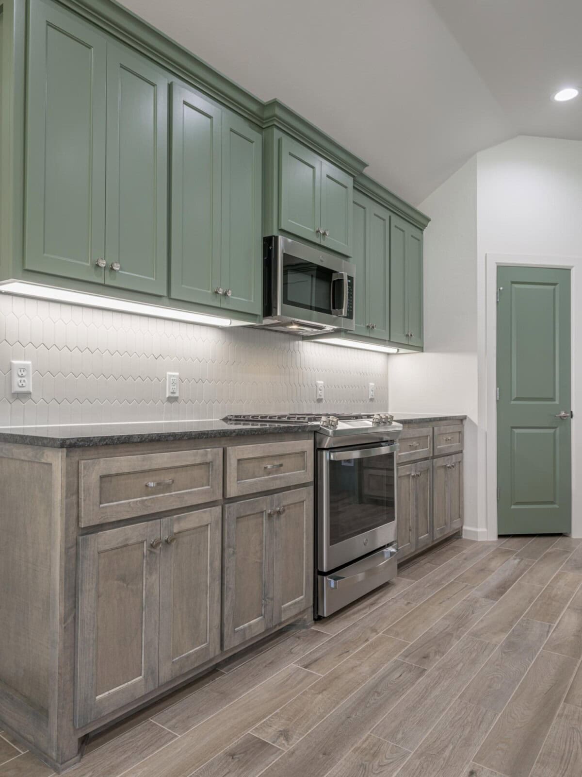 A kitchen with green cabinets and wood floors
