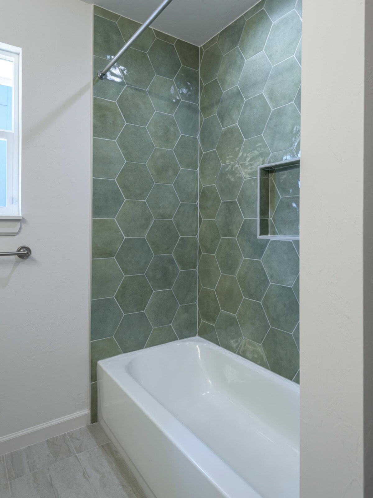 A bathroom with green tile and a tub