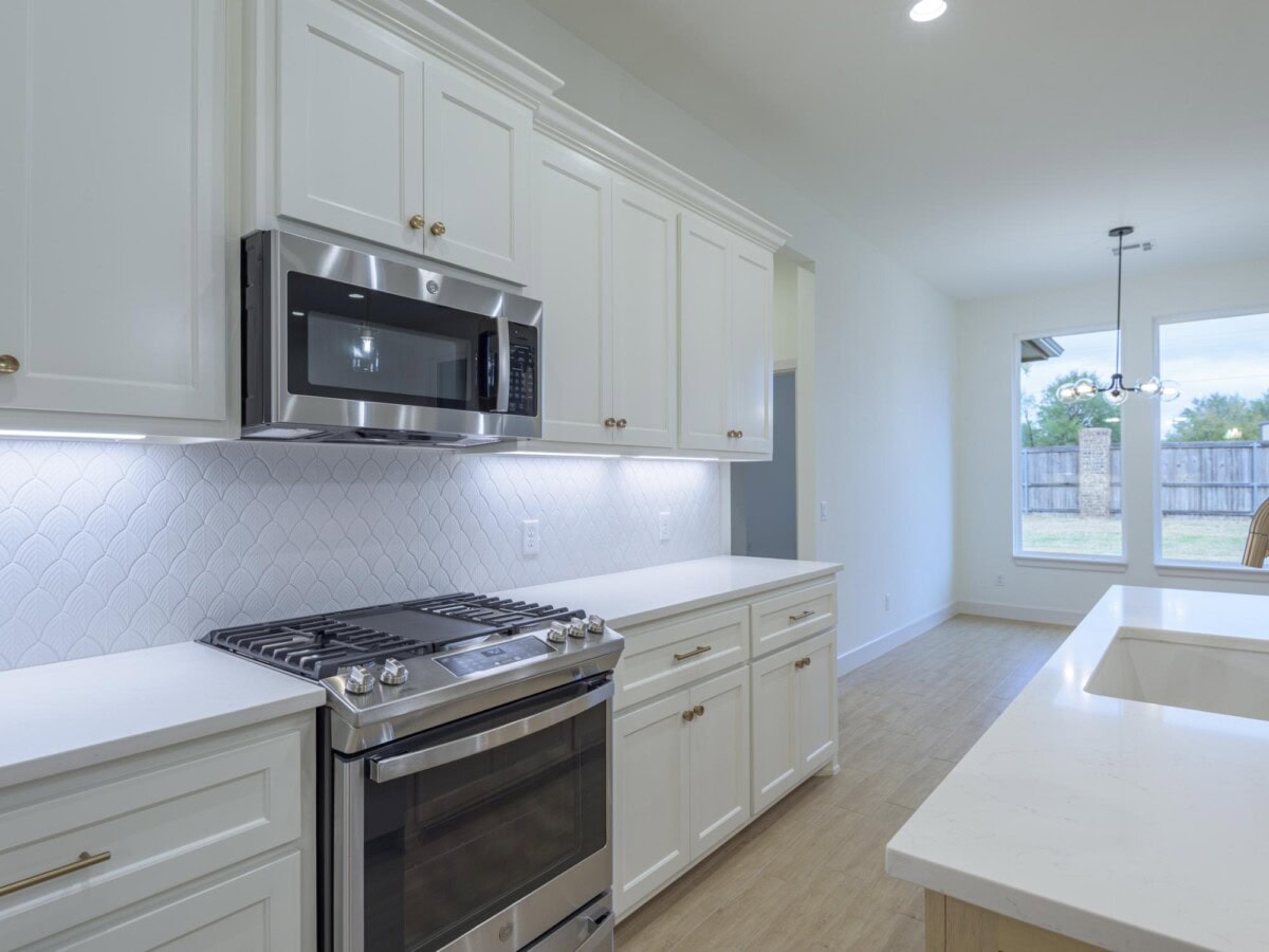 A kitchen with white cabinets and stainless steel appliances