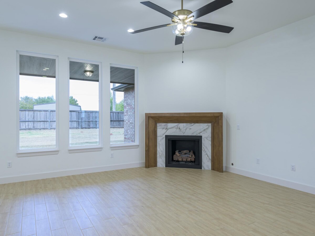A empty room with a fireplace and a ceiling fan