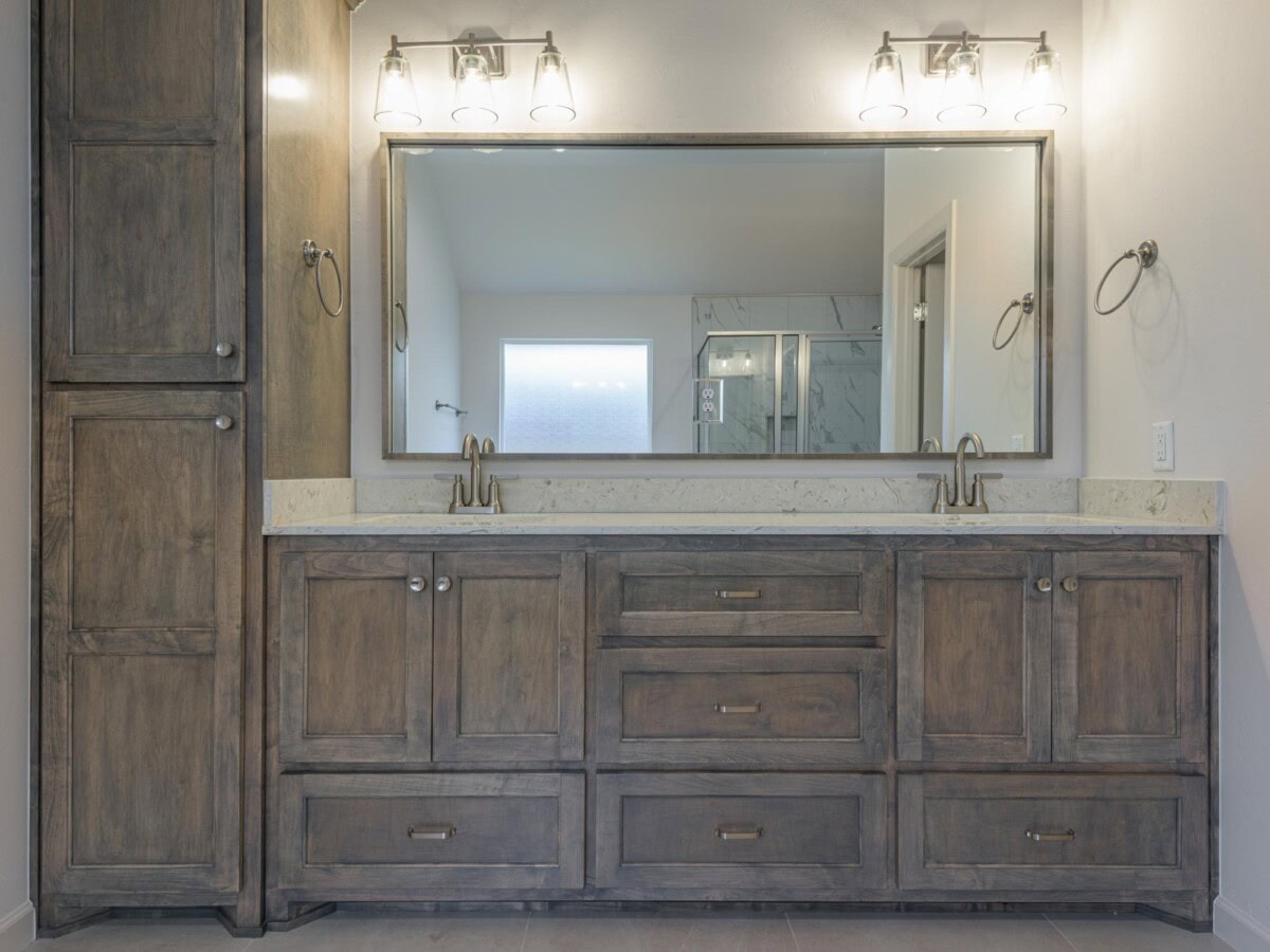 A bathroom with a large mirror and wooden cabinets