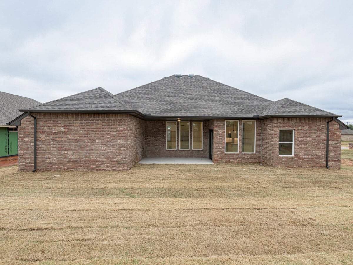 A brick house with a large yard in front of it