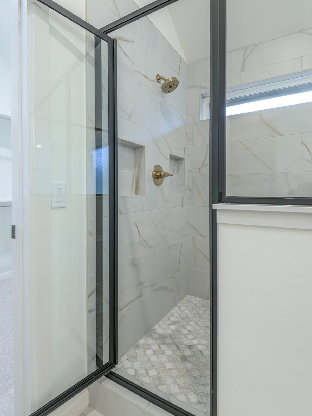 A bathroom with a glass shower door and a toilet