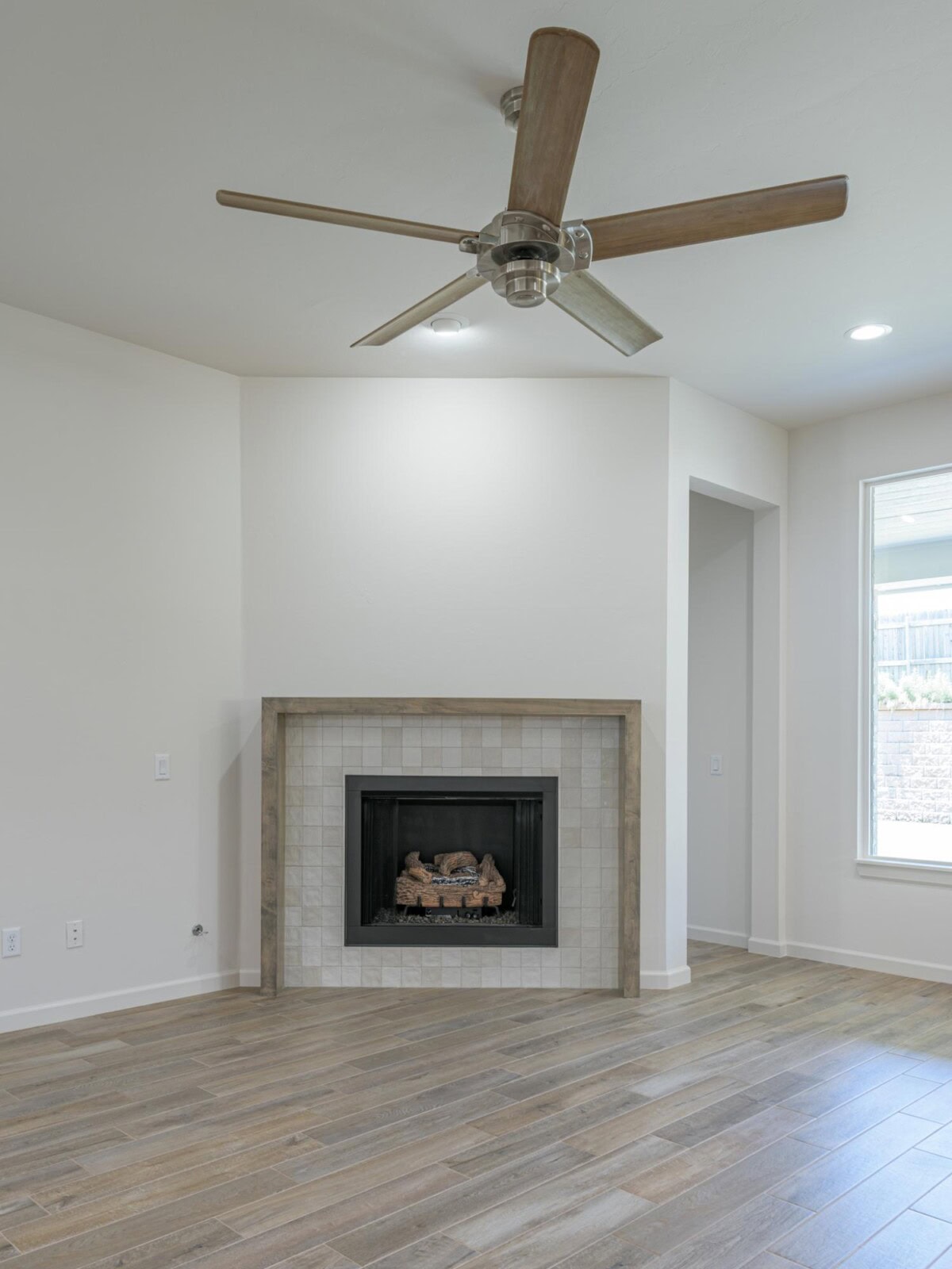 A empty living room with a fireplace and ceiling fan
