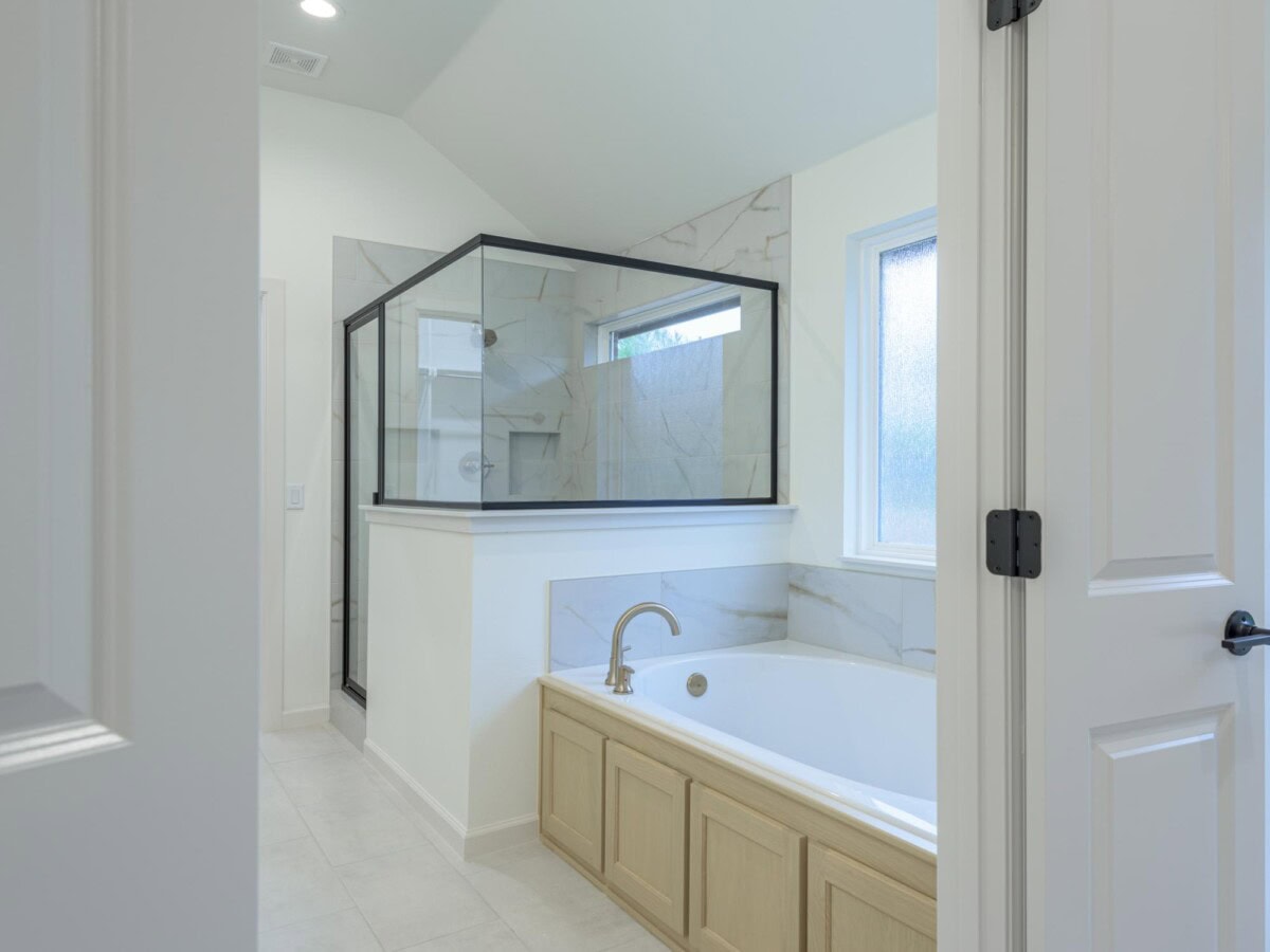 A bathroom with a glass shower door and a tub