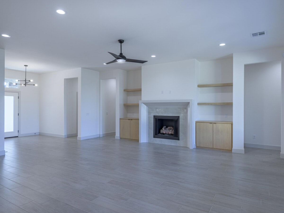 A large empty room with a fireplace and ceiling fan