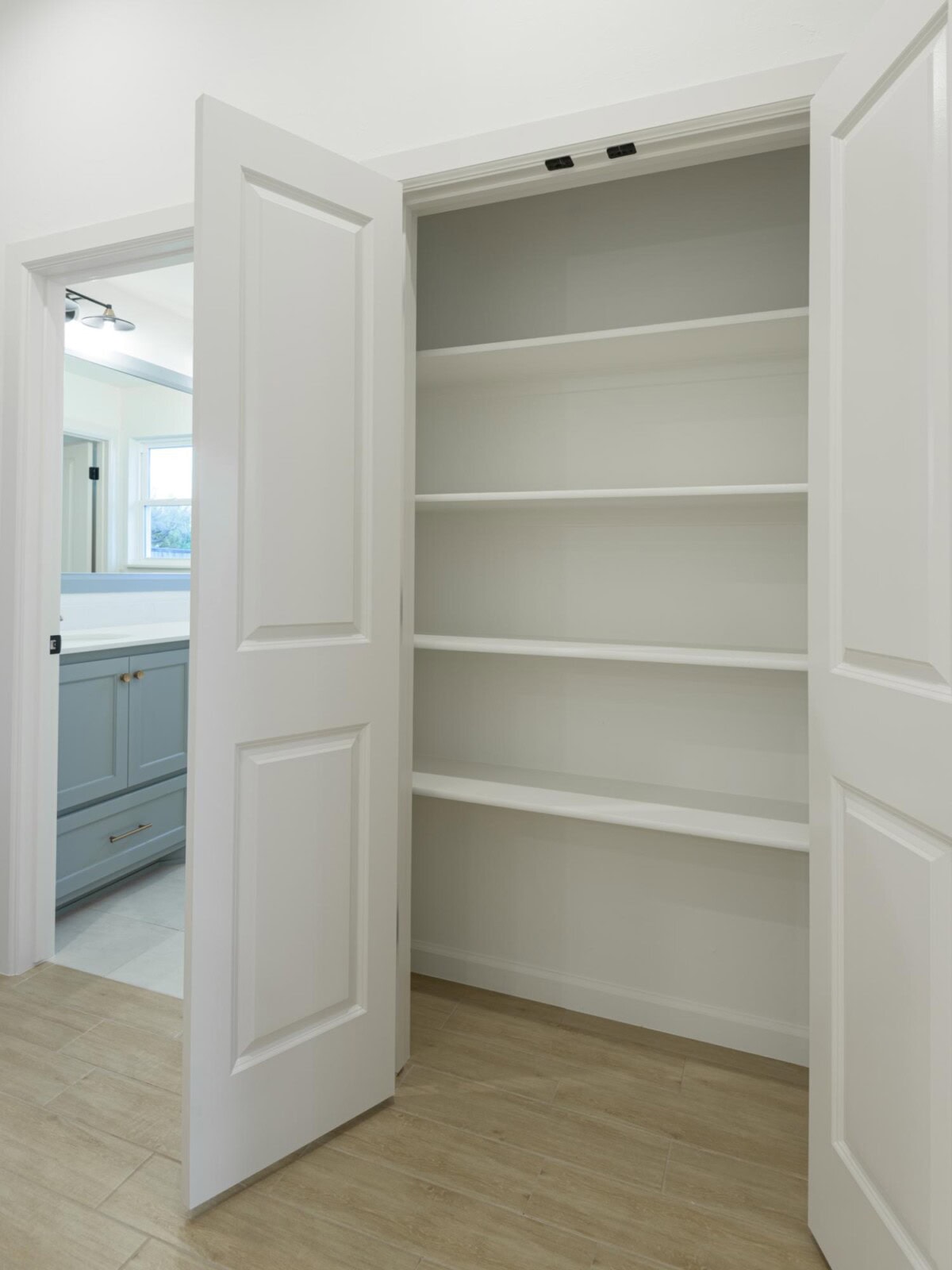 A white closet with shelves and open door