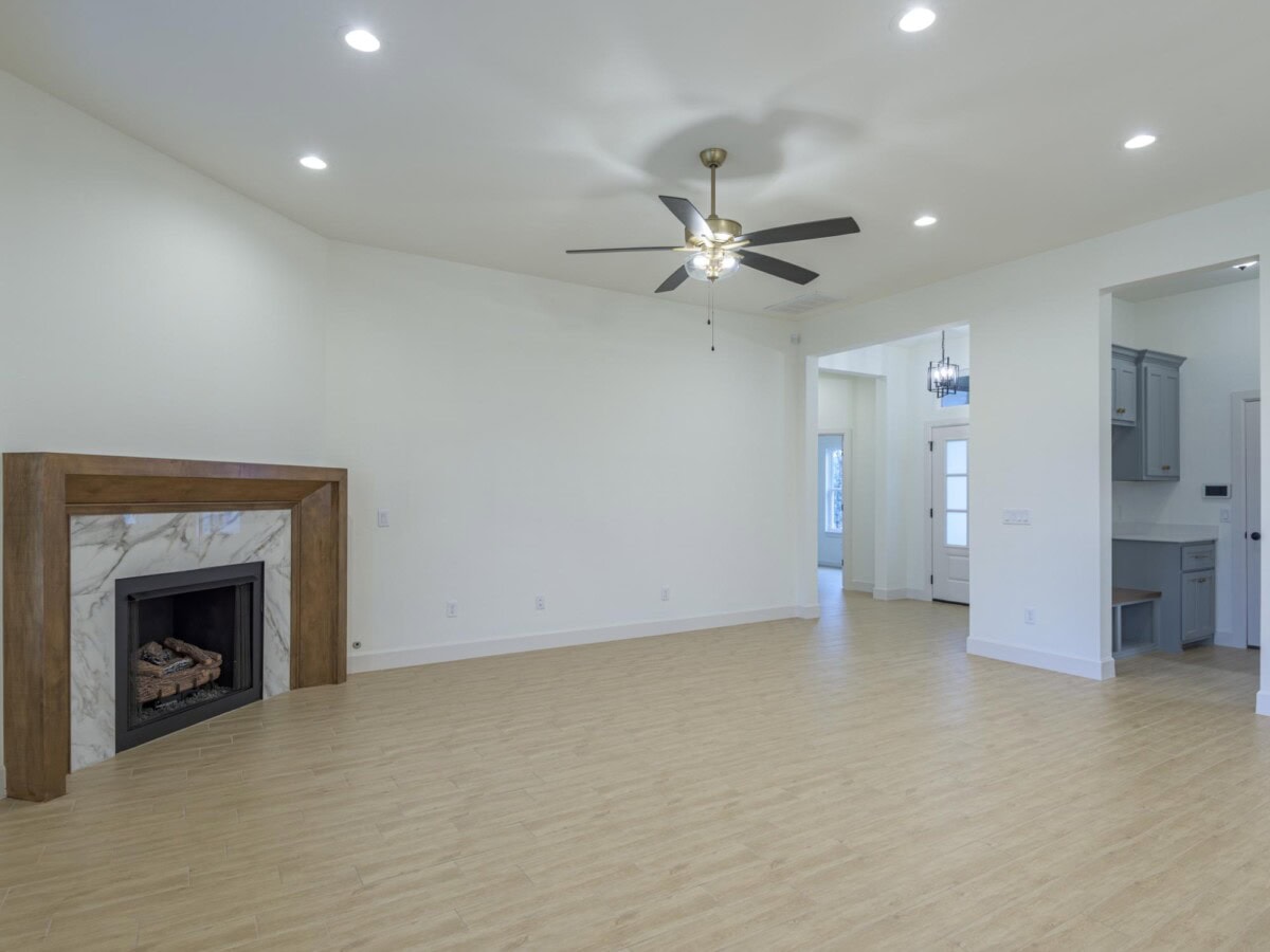 A empty living room with a fireplace and ceiling fan