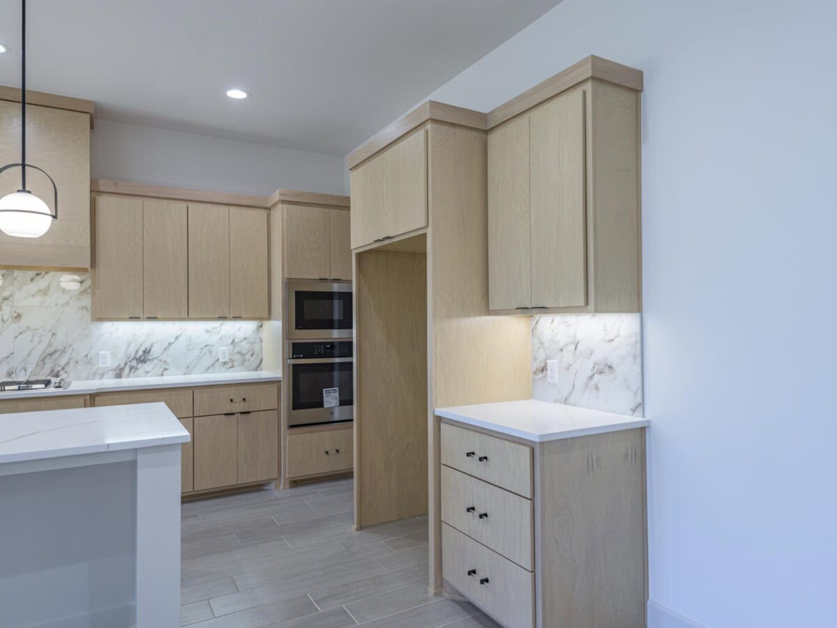 A kitchen with white cabinets and a marble counter top
