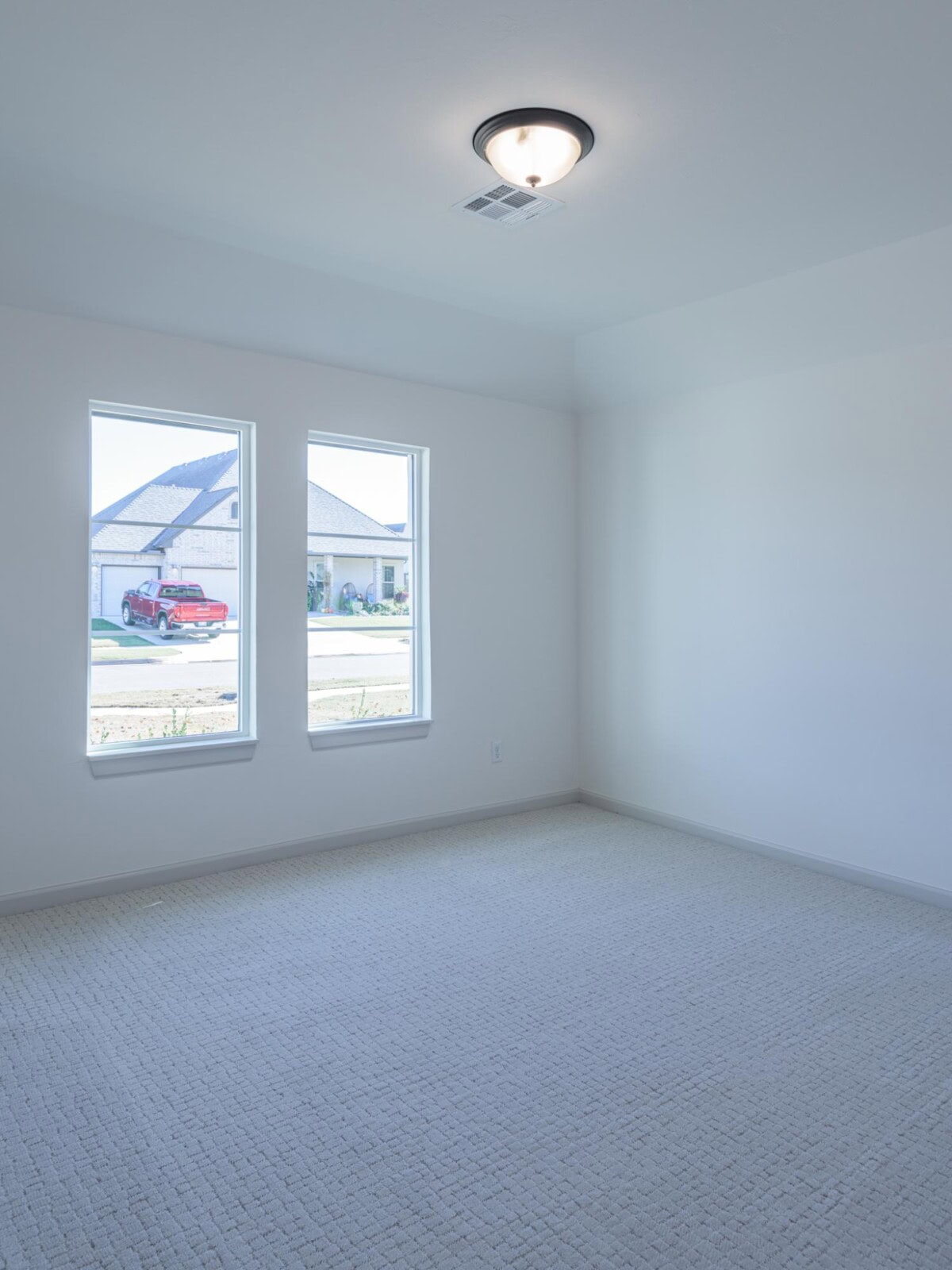 An empty room with a light fixture and carpet