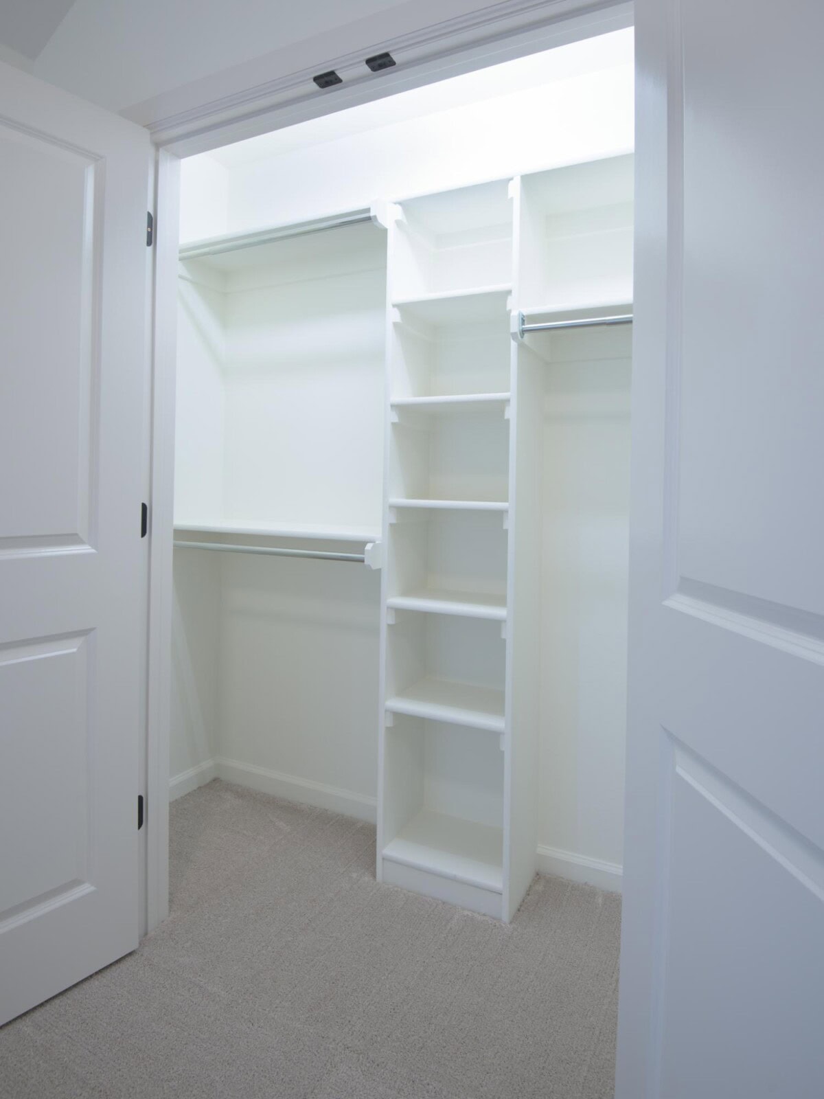 A closet with white shelves and open doors